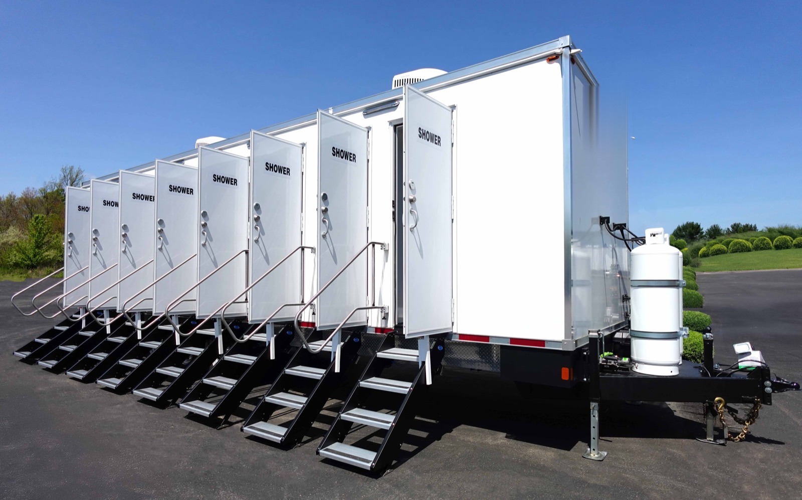 Eight station shower trailer from the tongue end with every stall door propped open and steps at each door